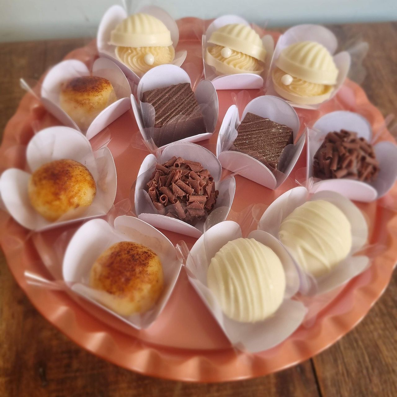 Docinhos variados em forminhas de papel sobre uma bandeja rosa